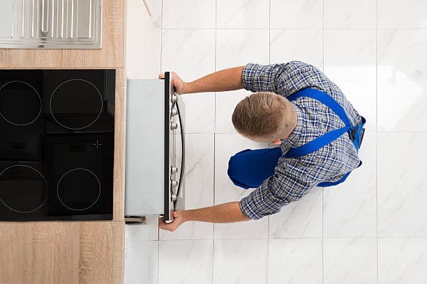 Techniker installiert und prüft den Anschluss eines Kochfeldes in einer Berliner Wohnung.